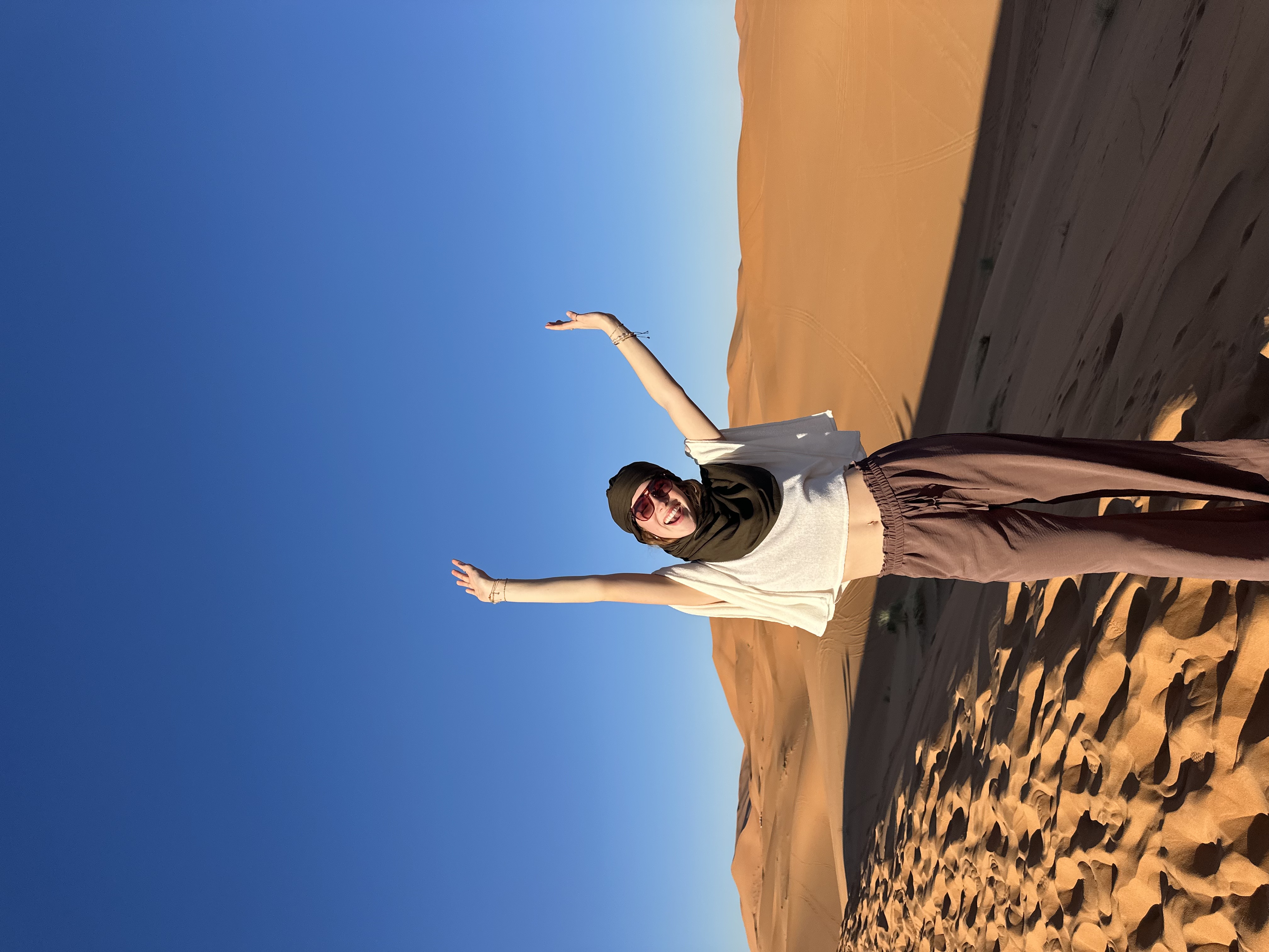 Kendyll celebrating with arms raised on desert sand dunes